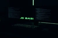 Dark‑mode developer workspace with a glowing green terminal and the phrase “JS BASICS,” illustrating JavaScript basics for developers.